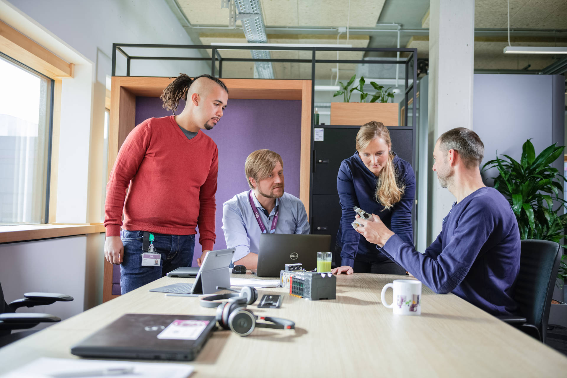 A diverse group of professionals collaborates in a modern office setting, engaging in a technical discussion around a laptop, reflecting an inclusive mindset and innovative team culture.