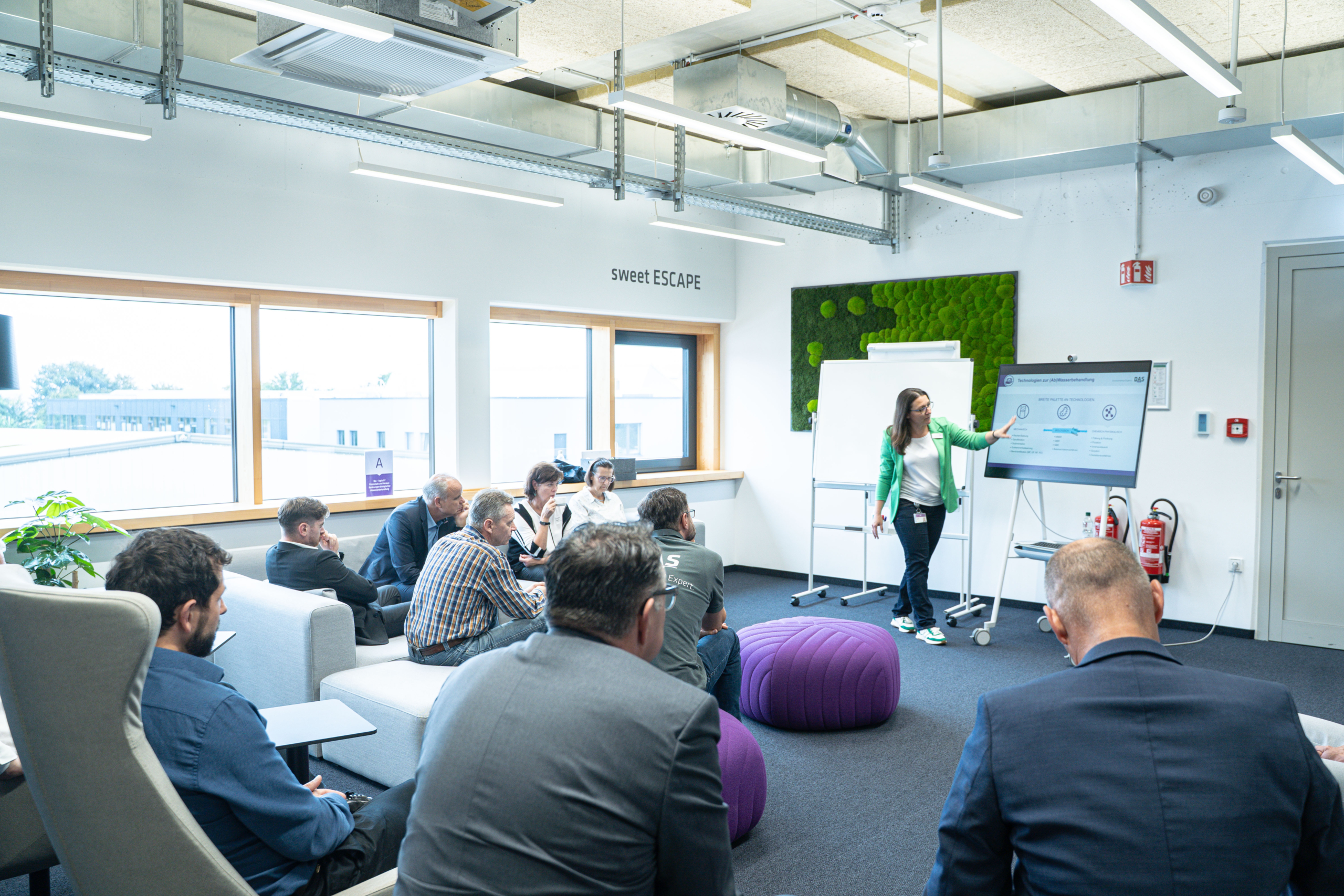 A group of people attentively watch a presentation in a modern, well-lit conference room