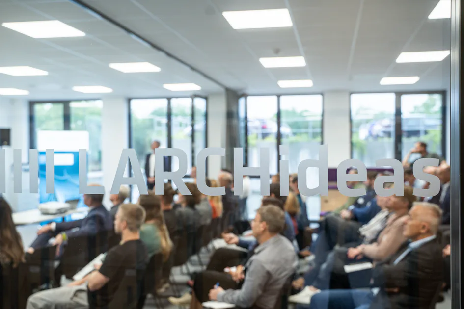2nd Industrial Water Day - Conference Room A diverse group of people attentively listen to a presentation in a modern, glass-walled conference room, highlighting a dynamic work environment.