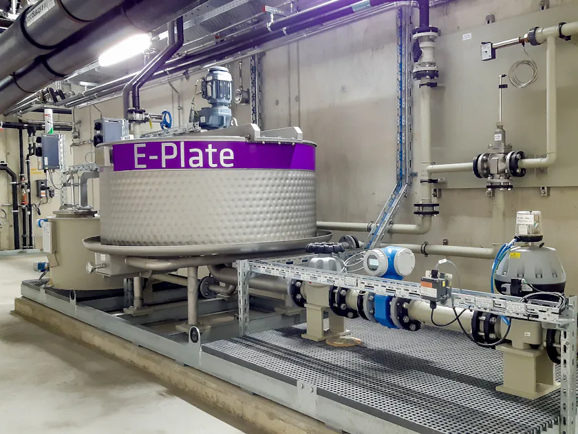 E-PLATE Heat Exchanger by DAS EE An industrial heat exchanger labelled ‘E-Plate’ stands in a modern plant room, surrounded by pipes and valves, manufactured by DAS Environmental Experts.