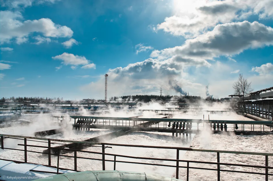Case study stock image Industrial plant with smoking chimneys, tall tanks, and pipes under a partly cloudy sky on a sunny day.