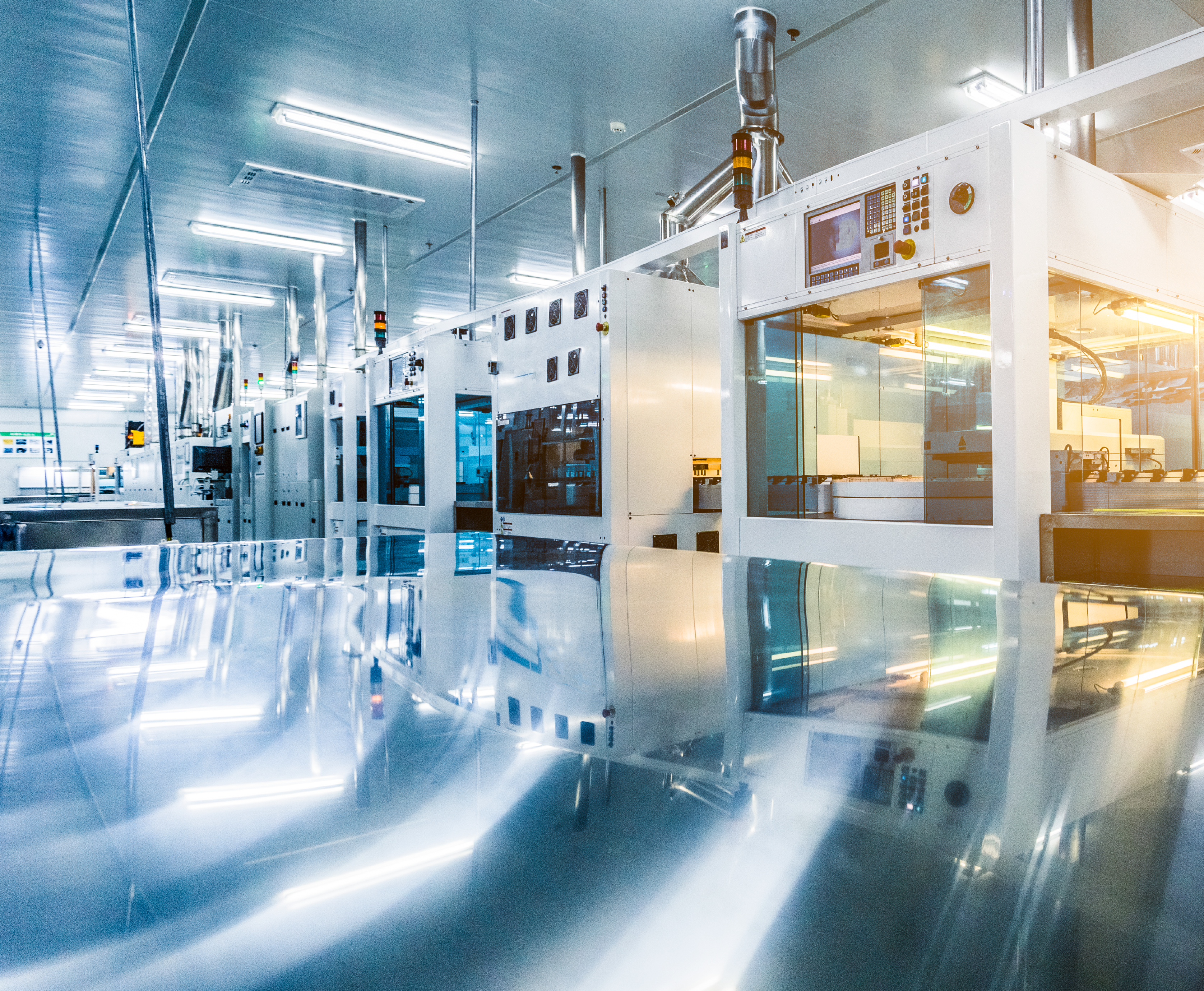 An automated production line with shiny metal surfaces stands in a bright factory hall. No people are to be seen.