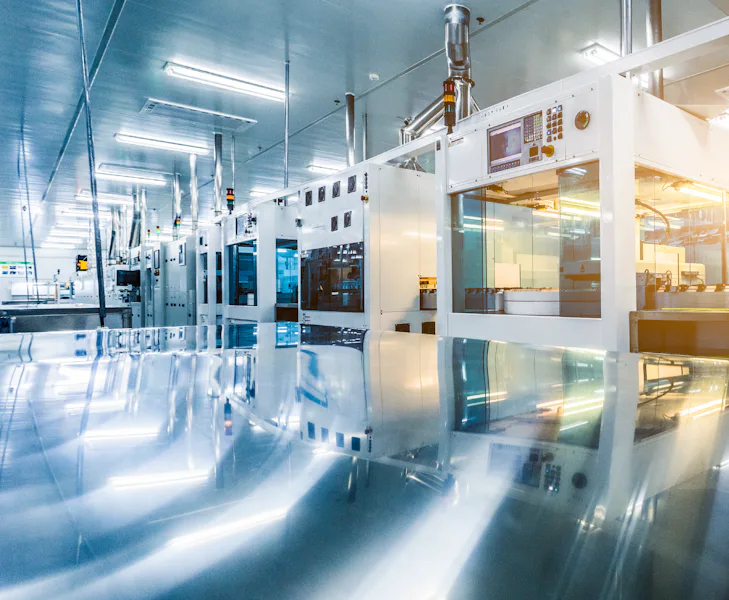 Technology_Product Portfolio An automated production line with shiny metal surfaces stands in a bright factory hall. No people are to be seen.