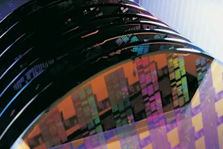 Silicon wafers A stack of colorful silicon wafers with intricate patterns is shown, highlighting the precision and complexity of semiconductor technology.