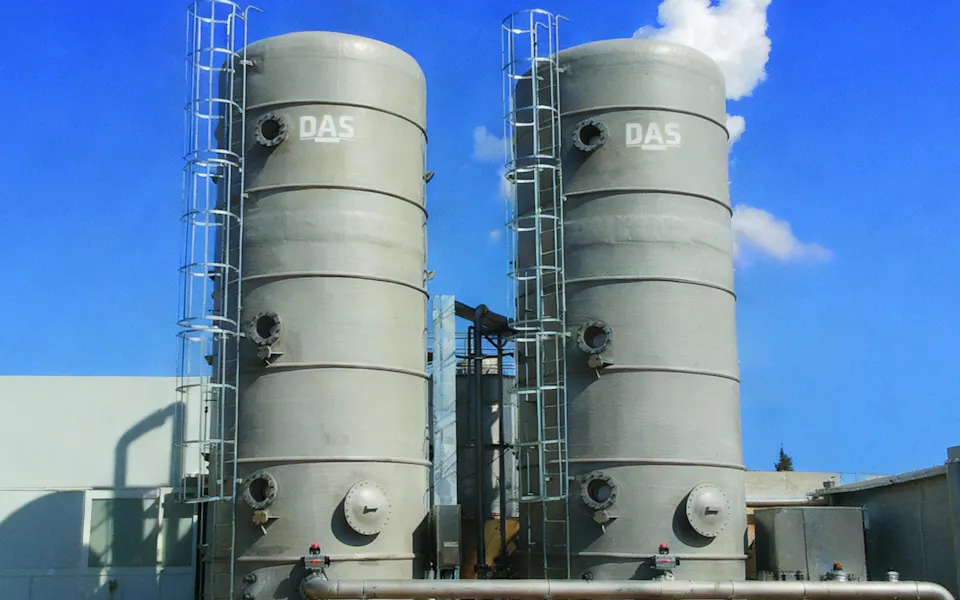 起司製造商 參考 兩個大型工業儲罐矗立於工廠外的草地上,背景為晴朗的藍天和白色雲朵。