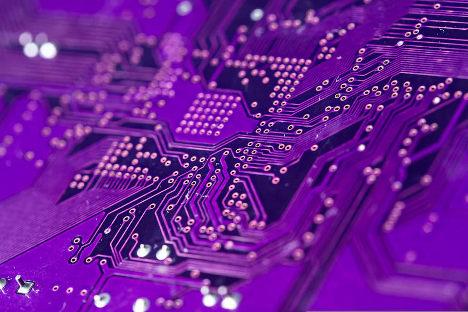 A close-up view of a purple printed circuit board showcasing complex electronic pathways and numerous copper connectors.