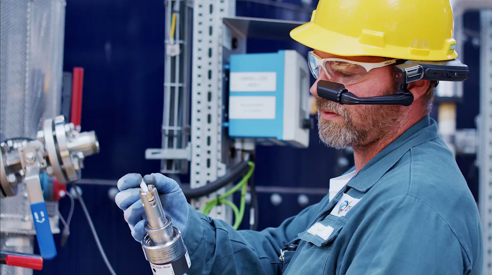 유지보수 및 수리 작업(BUW) 안전모와 보안경을 착용한 남성 작업자가 산업 현장에서 기술 장비를 사용하고 있습니다.