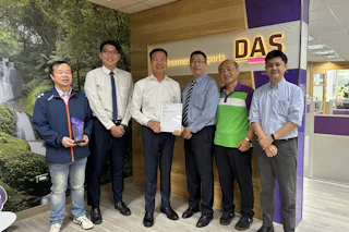ISO certification DAS Taiwan 2025 Six individuals stand together in an office in front of a wall with a nature mural and a sign that reads "DAS"; one person holds a certificate while another holds a purple award.