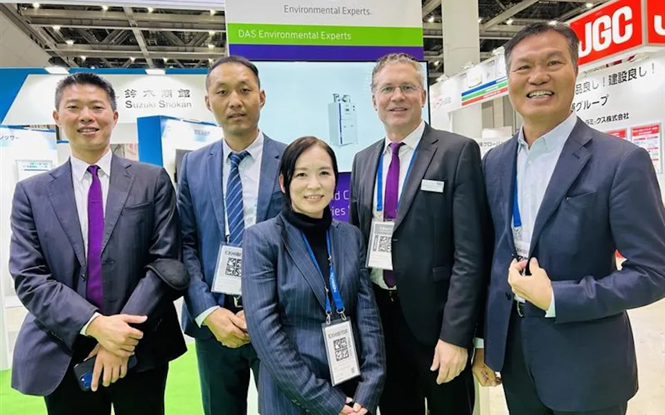 Impressions SEMICON Japan Five people are standing together inside a convention center, wearing business attire, with a banner for DAS Environmental Experts visible in the background.
