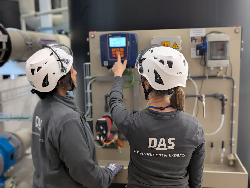 DAS Engineer checking Water Treatment Plant Two individuals wearing helmets and DAS-branded gear operate a sophisticated control panel in an industrial setting, highlighting environmental technology solutions.