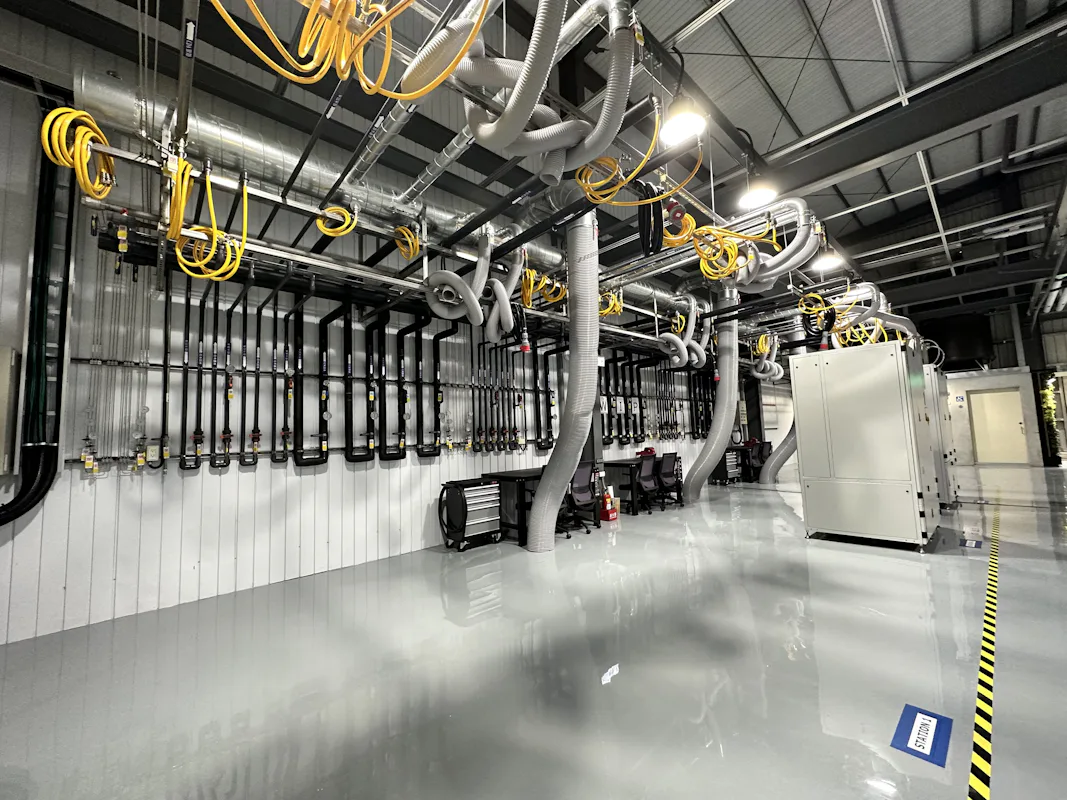 DAS TW 工廠 這張圖片展示了一個現代化的工業設施內景,具有多條管道和電纜系統,整齊排列在拋光的灰色地板上,增添了科技感;設施內的複雜機械設置和明亮照明突顯出工業科技的先進性。