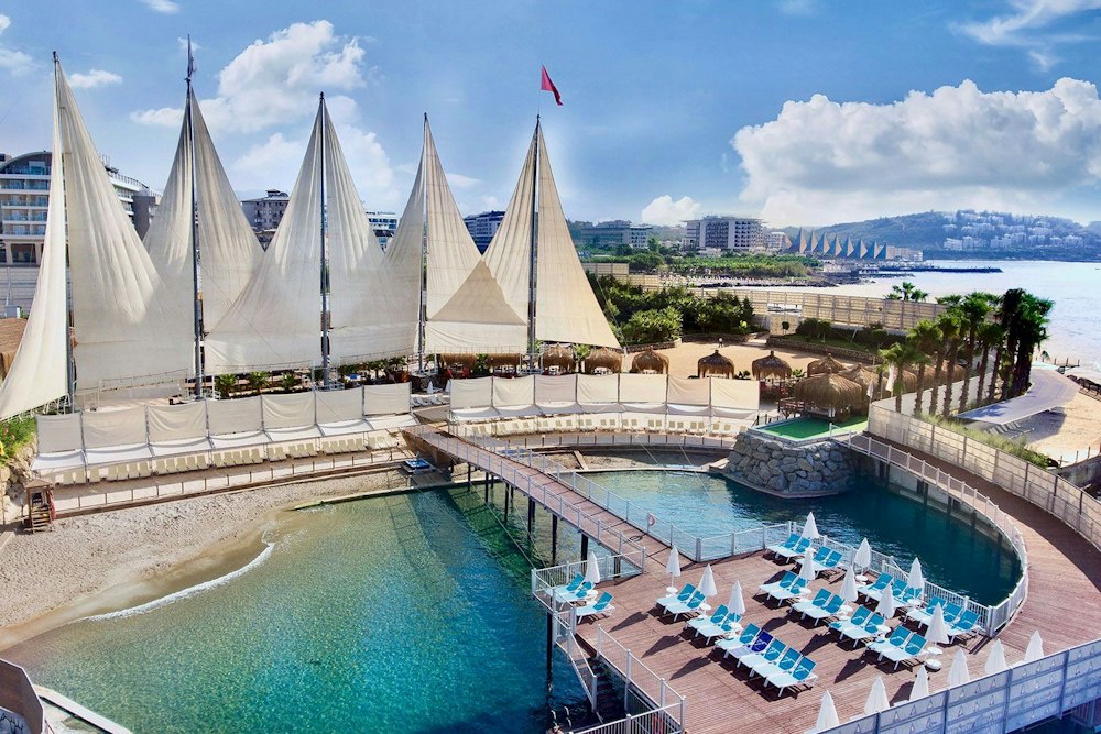 Beach under white sail canopies at Adenya Hotel & Resort