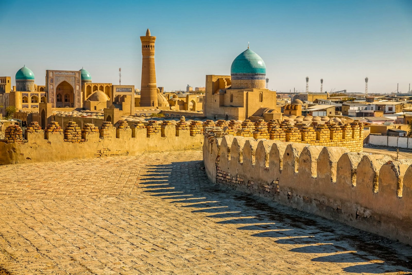 Vue à travers le mur de la forteresse de la vieille ville avec minarets et madrasas de Boukhara
