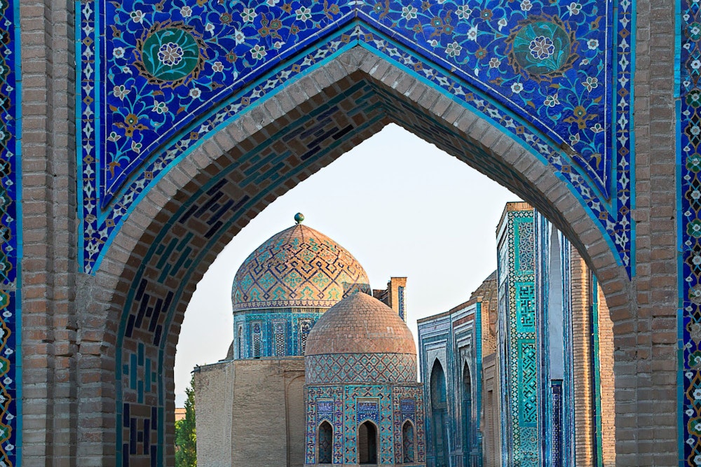View over the mausoleums and domes of the historical cemetery of Shakhi Zinda through an arched gate
