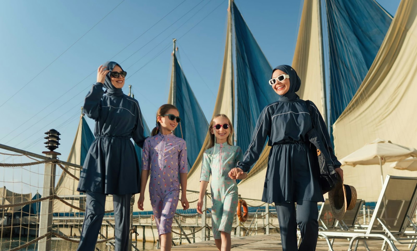 A mother and three daughters walking past sail canopies at a resort in Antalya