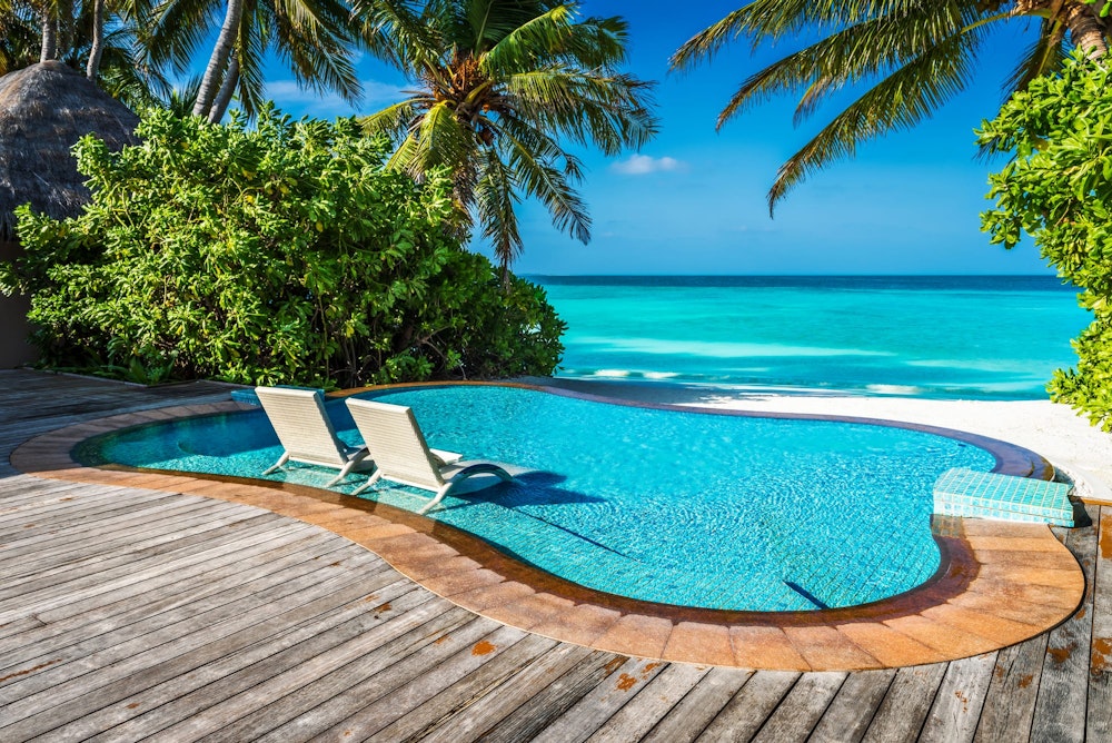 Мальдивы: частный бассейн у океана с шезлонгами, погруженными в воду