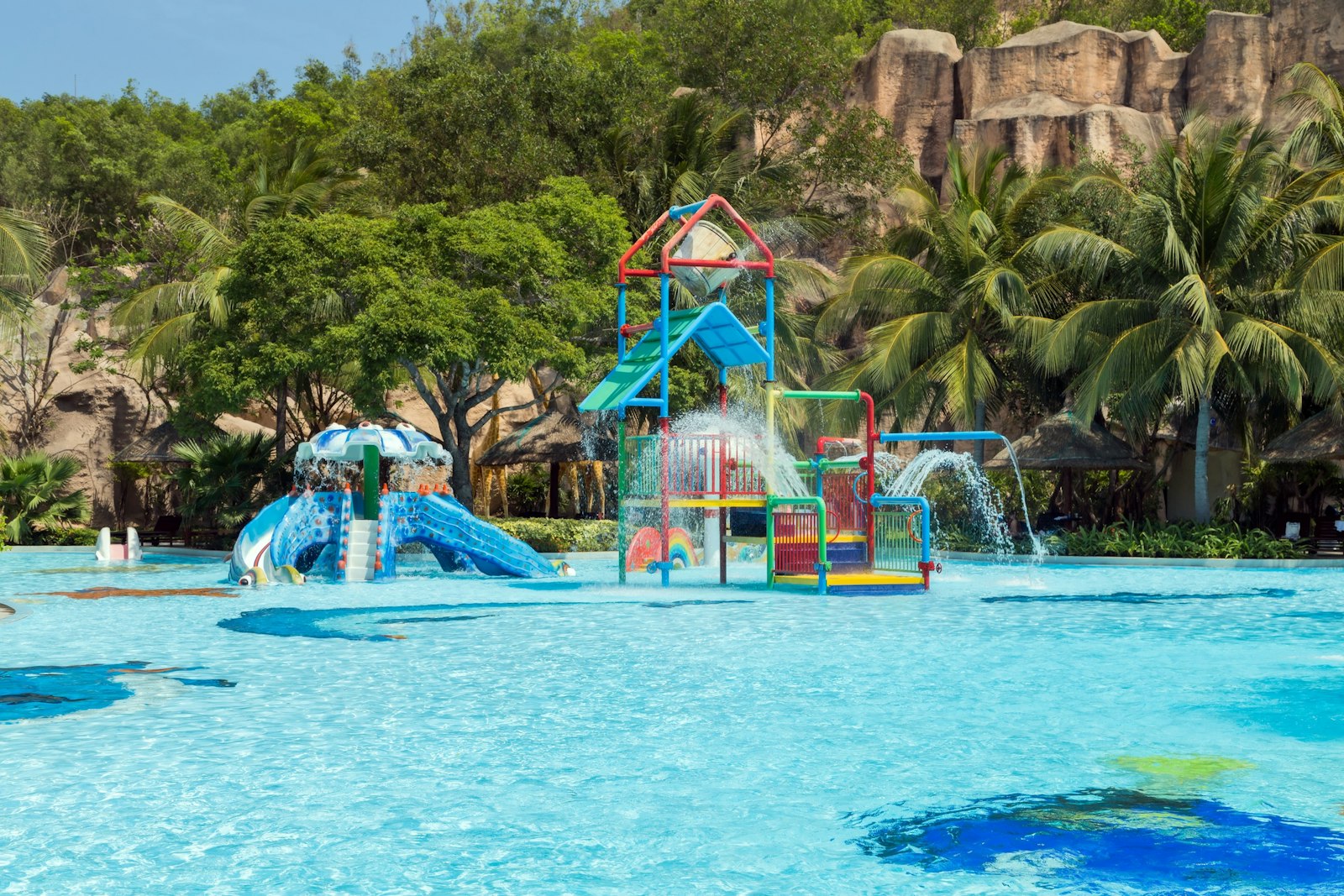 Colourful water park slides in a resort pool surrounded by palm trees
