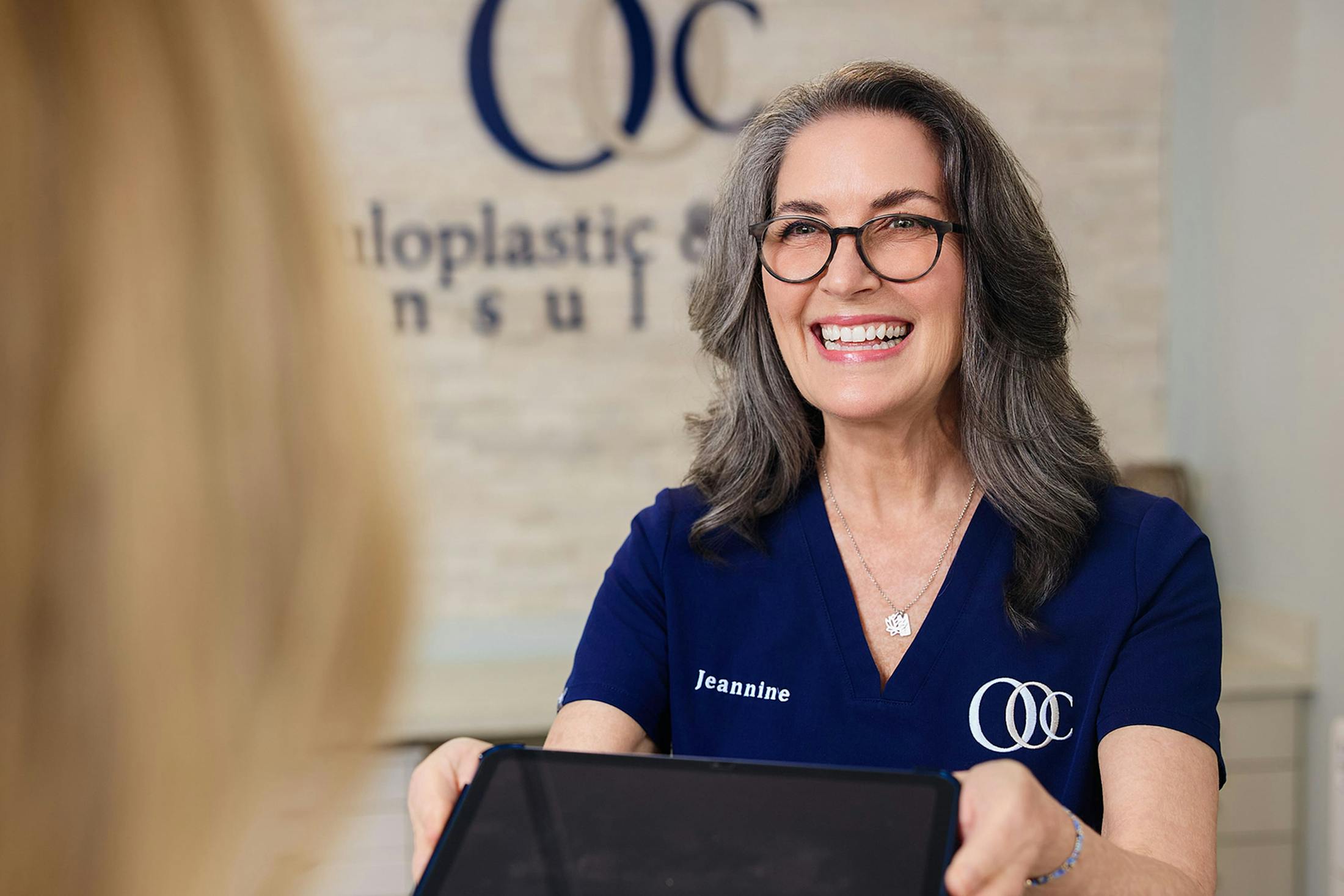 receptionist smiling and handing ipad to patient