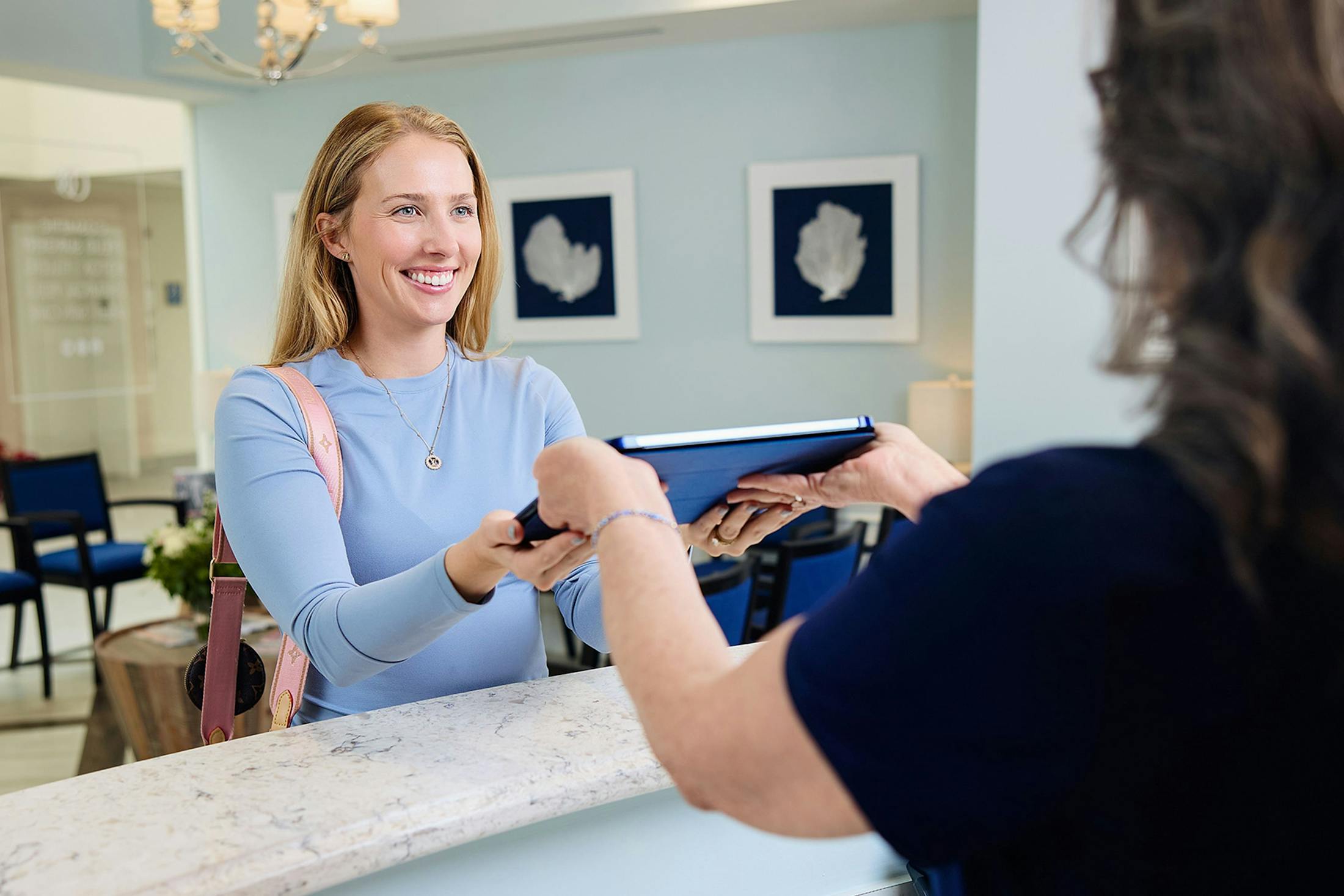 patient smiling at receptionist while getting an ipad from her