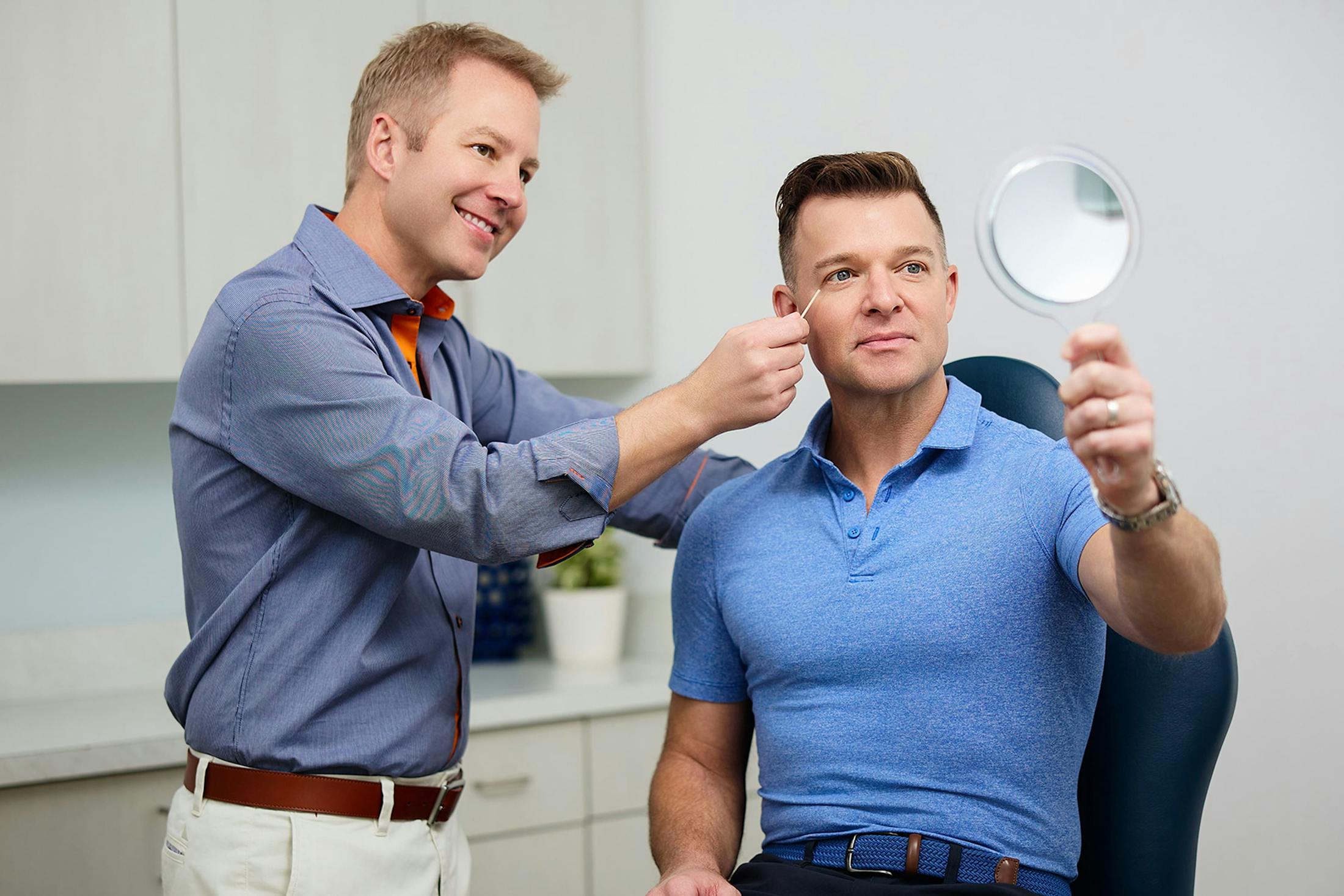 Dr. Connor looking at patient's eyes while he looks at handheld mirror