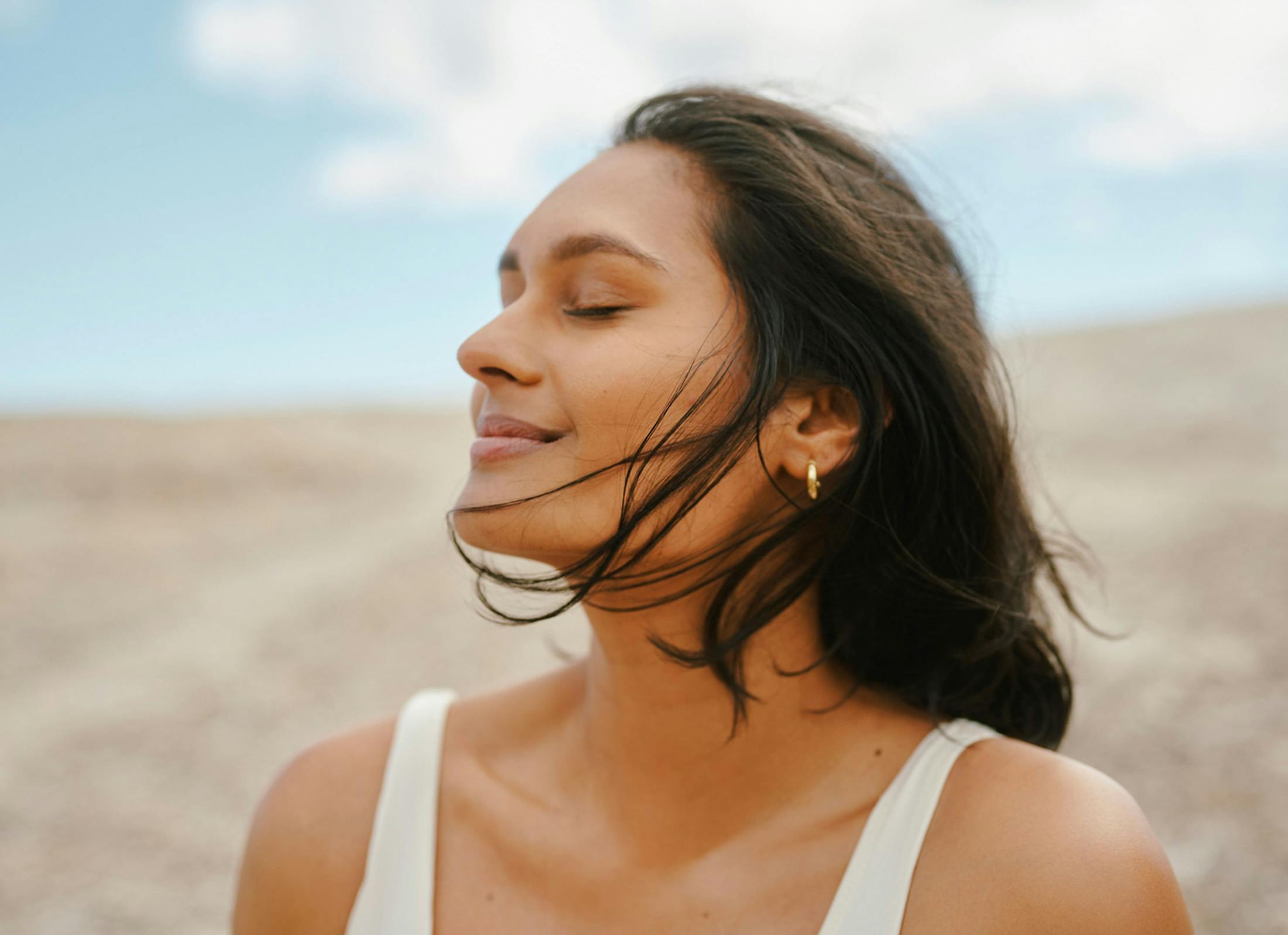 woman outdoors with her eyes closed facing the left
