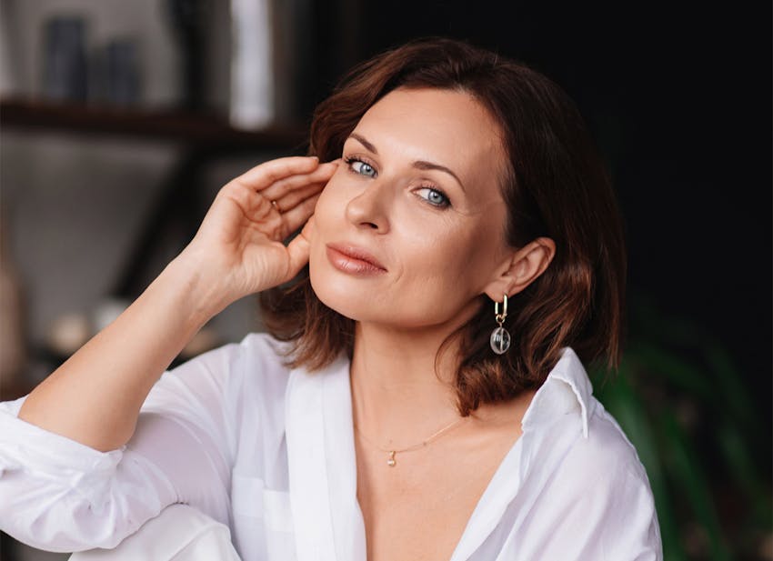 woman with short brown hair with her hand touching her cheek