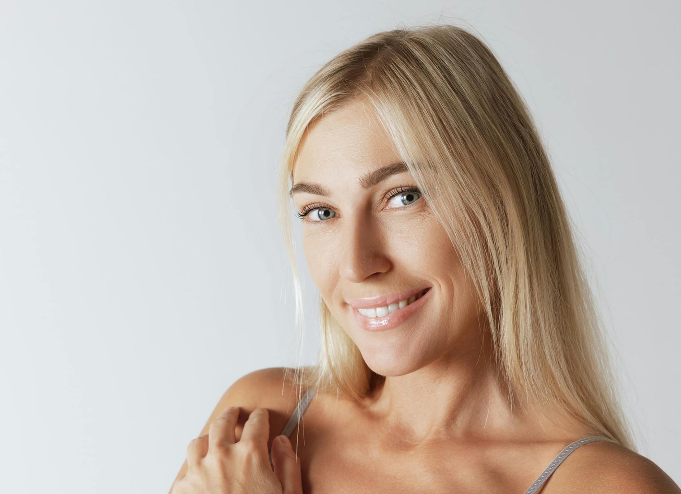 woman smiling with her hand touching her shoulder