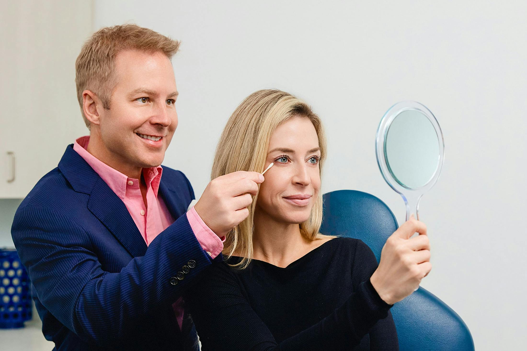 Dr. Connor helping patient with her eyes while looking into mirror