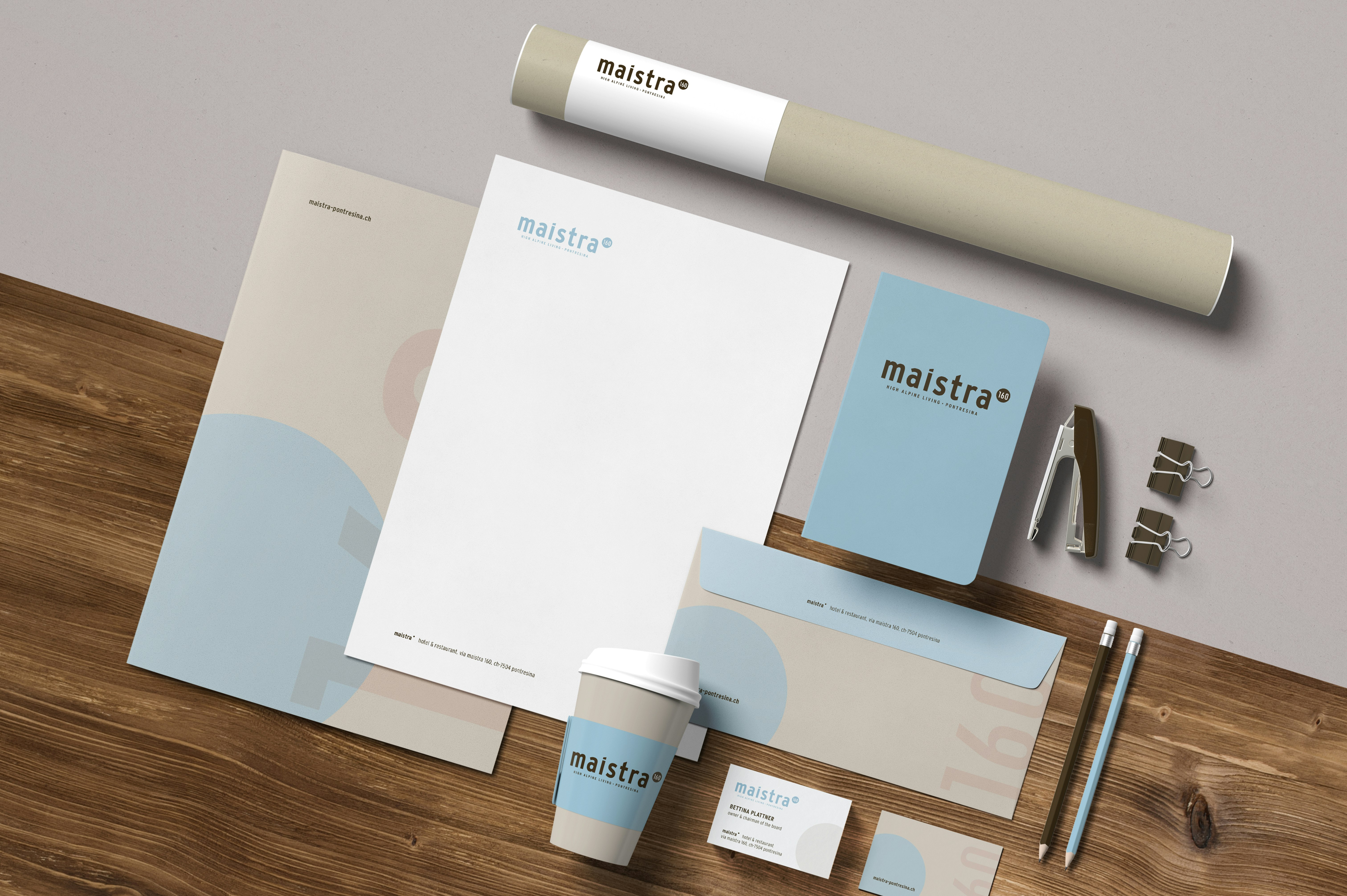 Corporate Design von Maistra mit Briefpapier, Visitenkarte, Notizbuch, Kaffeebecher und Umschlägen in Beige und Blau.