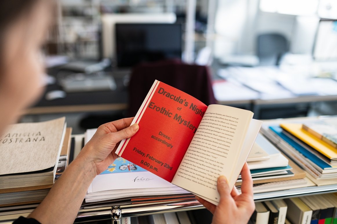 Aufgeschlagenes Buch mit roter Seite „Dracula’s Night of Erotic Mystery“.