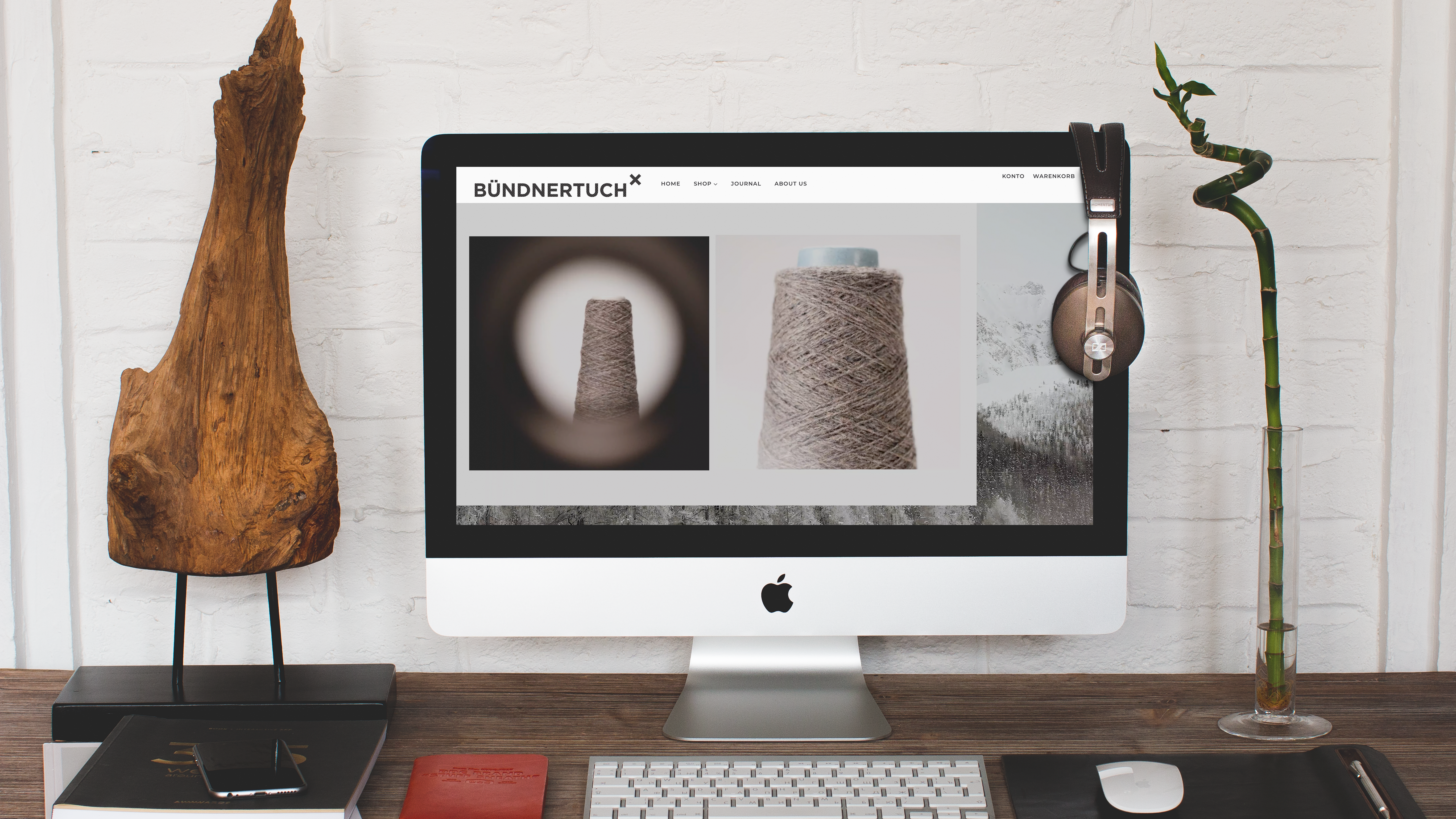 Schreibtisch mit iMac und Bündnertuch-Webseite.