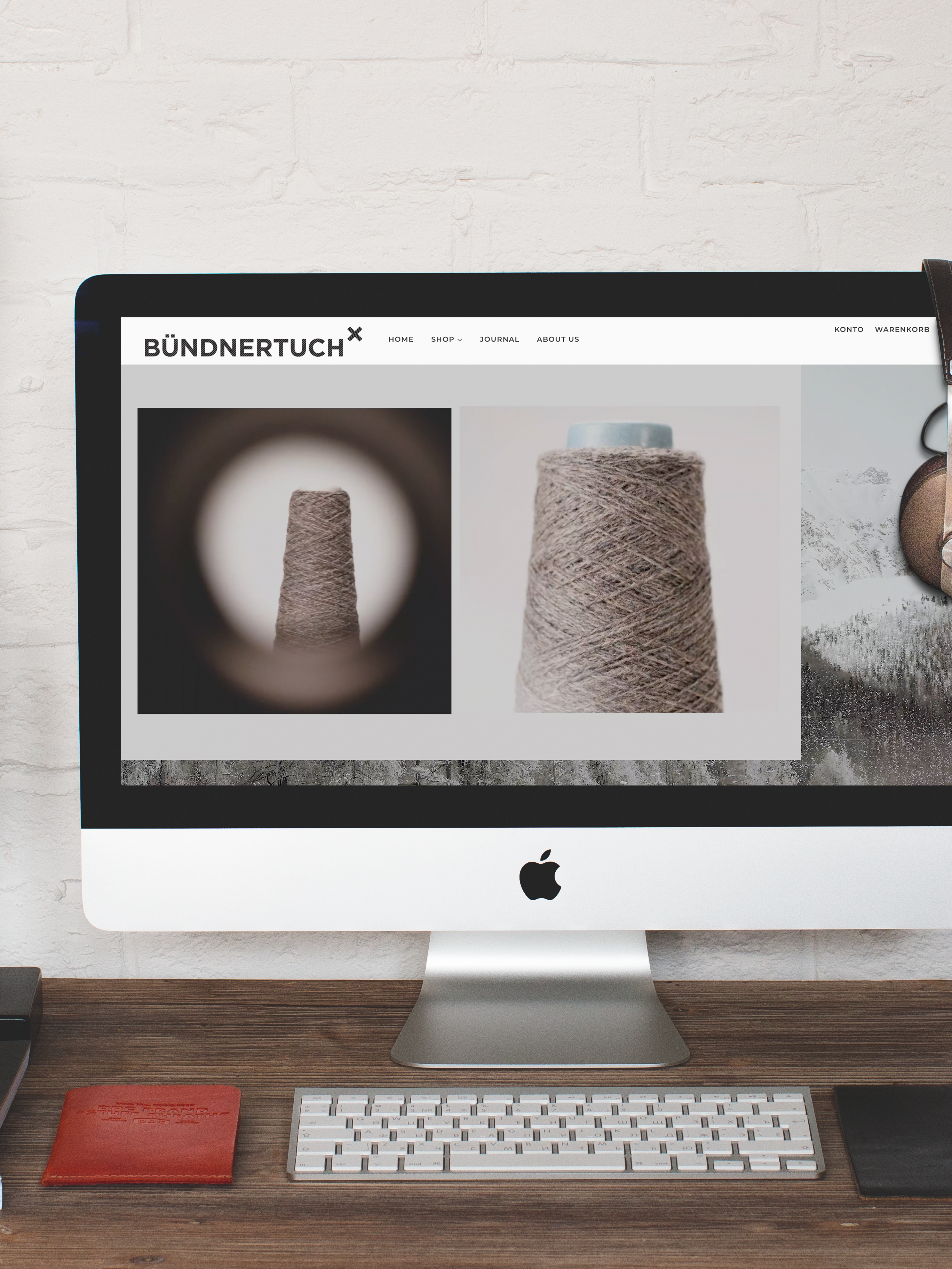 Schreibtisch mit iMac und Bündnertuch-Webseite.