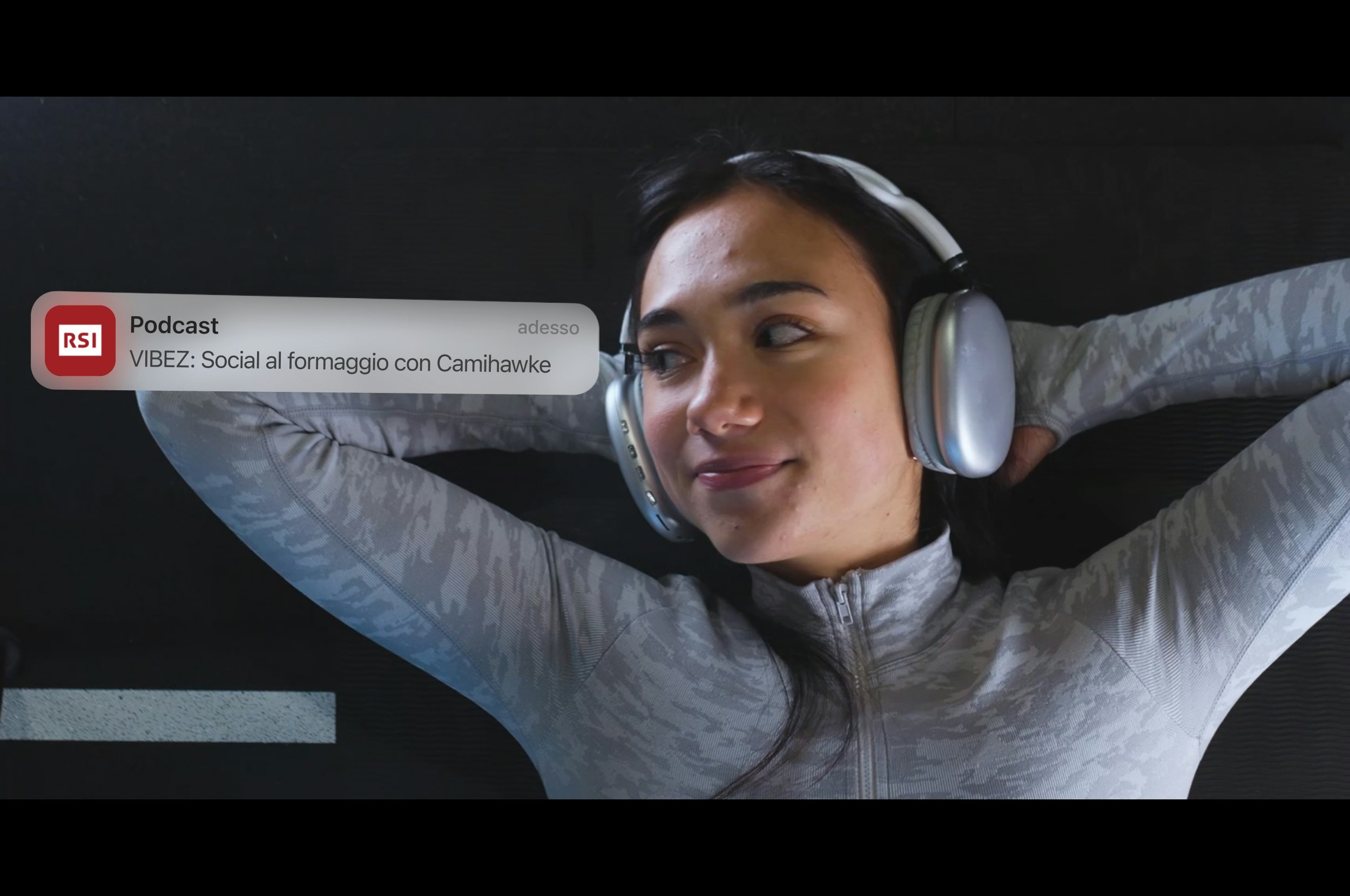 Young woman wearing headphones in gray outfit with RSI podcast notification “VIBEZ”.
