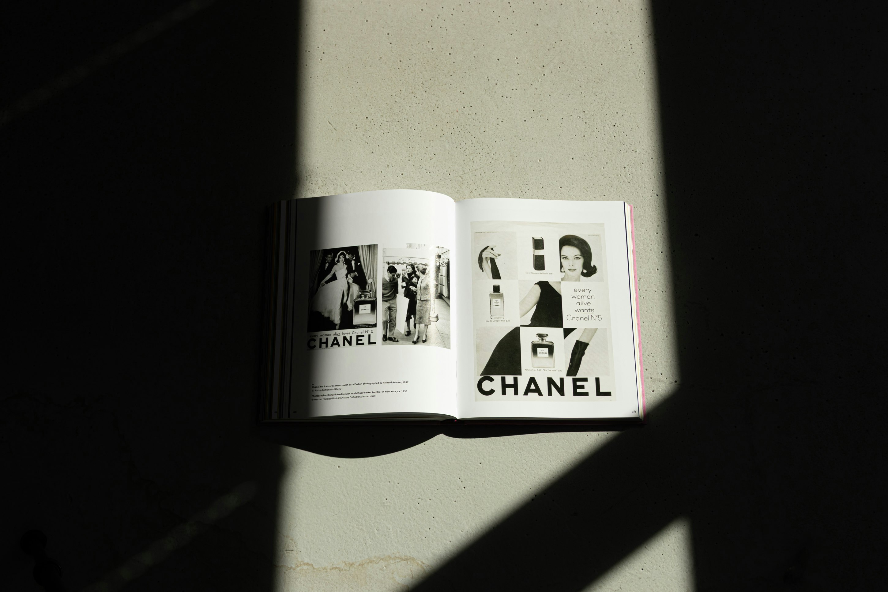 Aufgeschlagenes Buch mit historischen Chanel-Werbeseiten in Schwarzweiss, inszeniert im Spiel von Licht und Schatten.