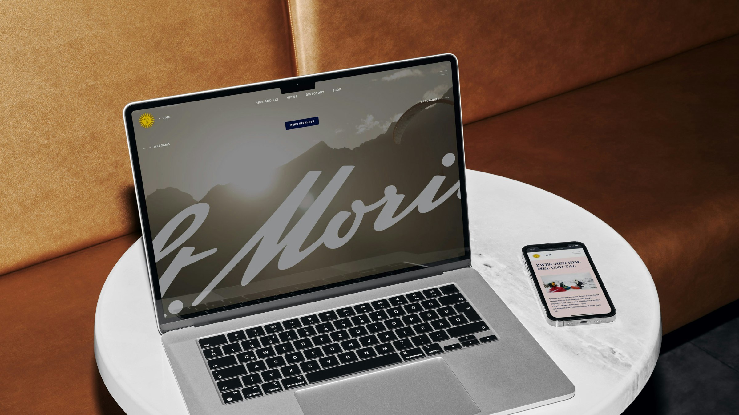 An open laptop and a smartphone display the St. Moritz website featuring the large logo and scenic background.