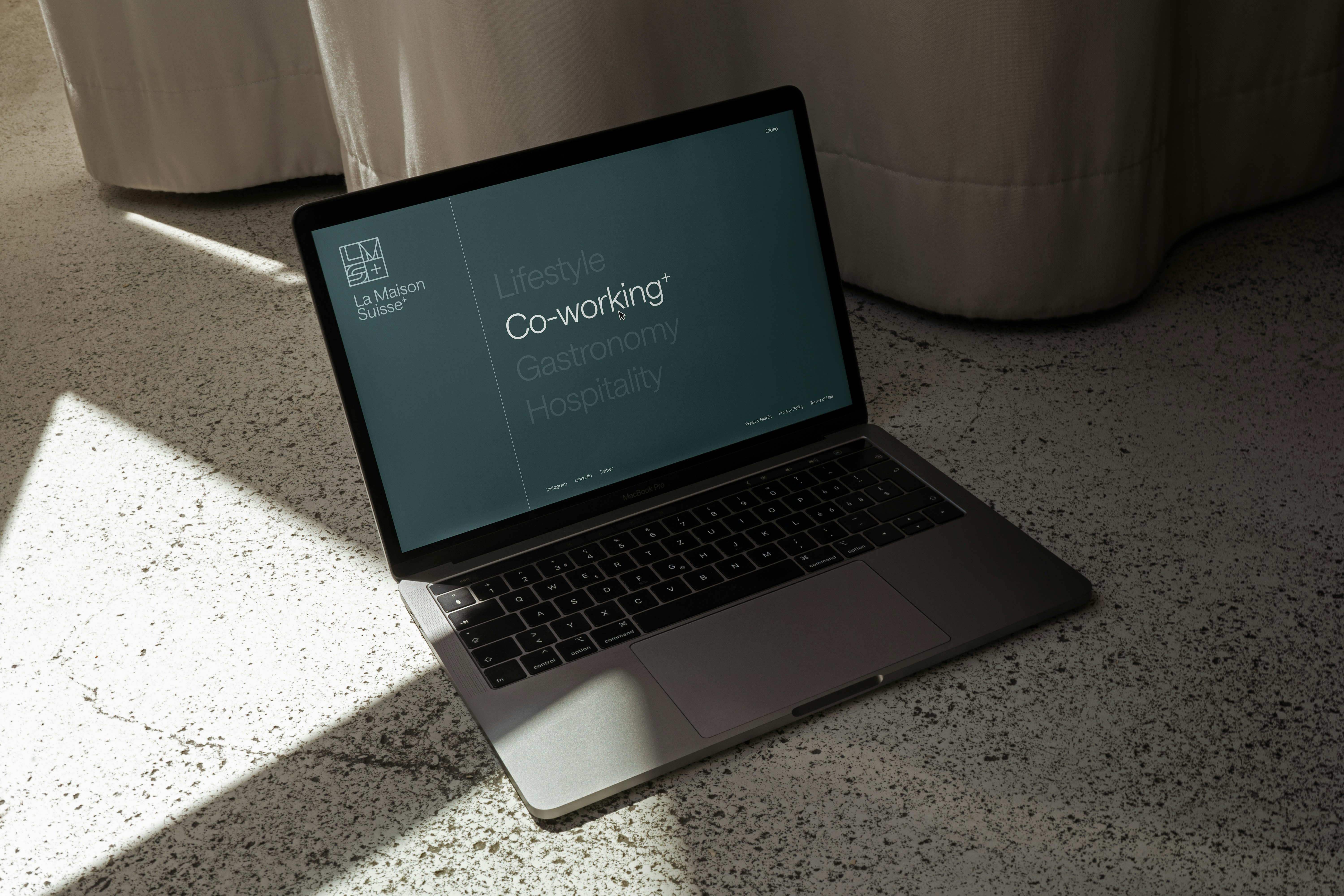 Laptop mit der La Maison Suisse Website, Fokus auf den Bereich „Co-working+“, in minimalistischer Ästhetik und warmem Licht fotografiert.