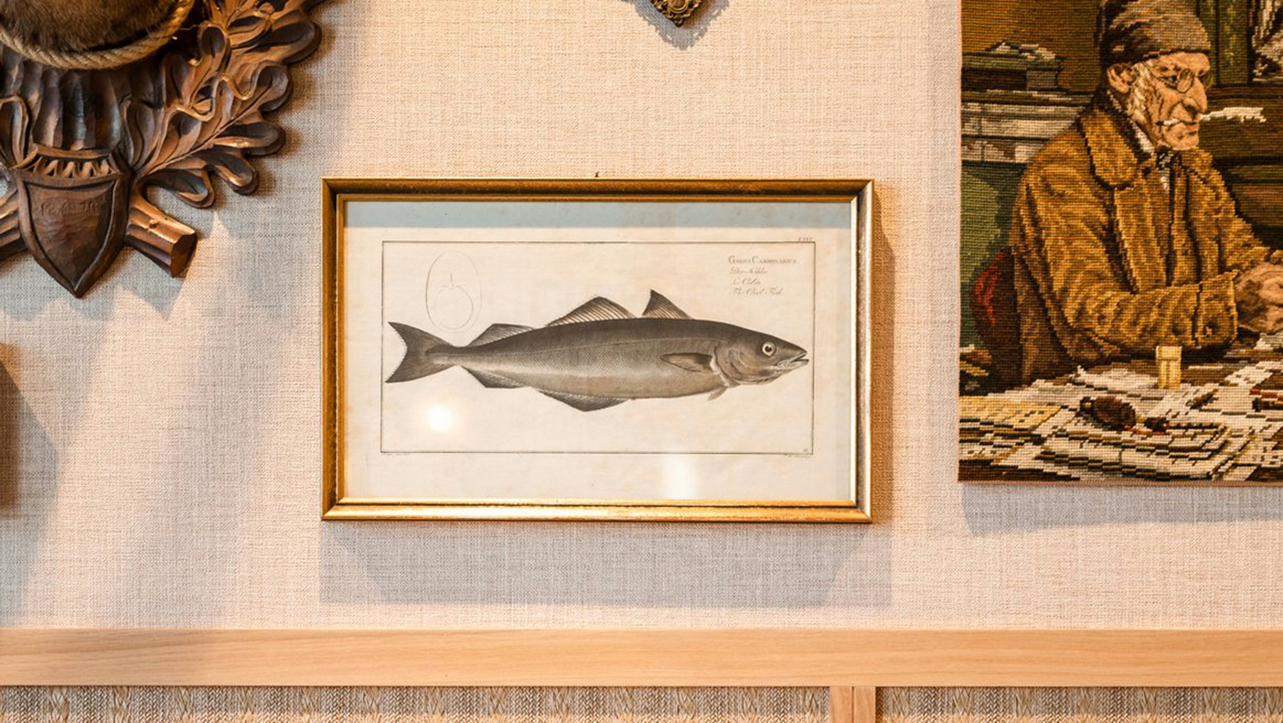 Detailaufnahme einer Wand im Hotel Steinbock mit Bildern und Stoffsofa.