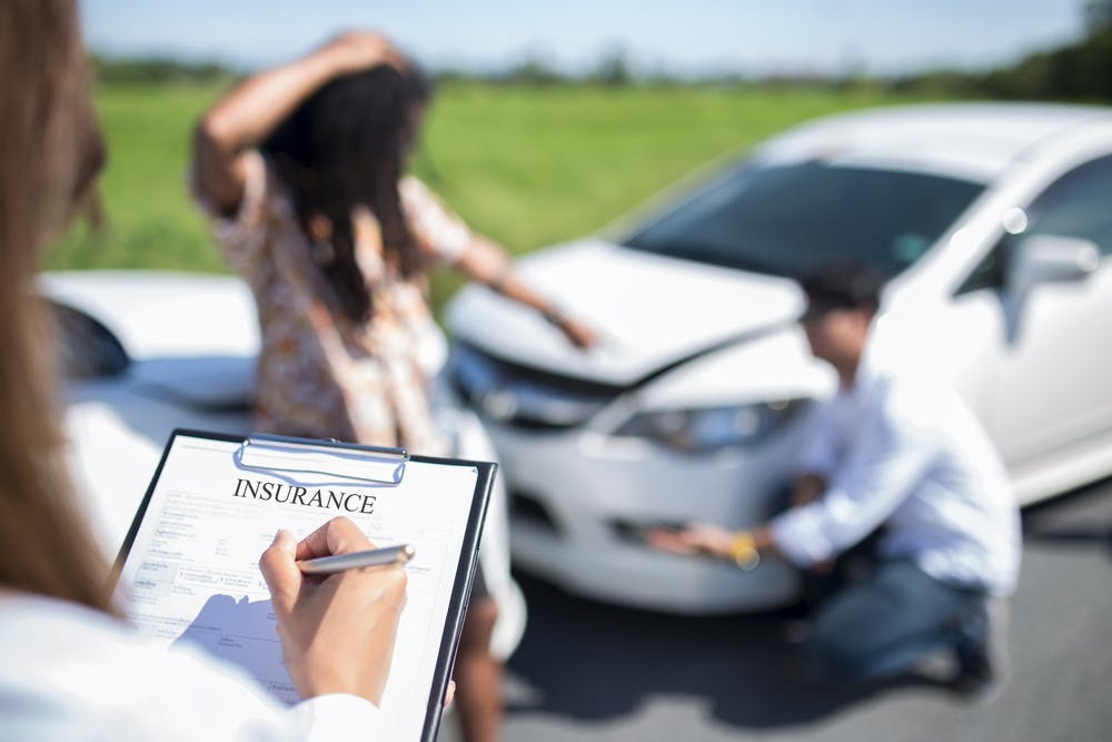 Insurance Agent at Accident Scene Insurance Agent Inspecting Car Accident With Owners in the Background