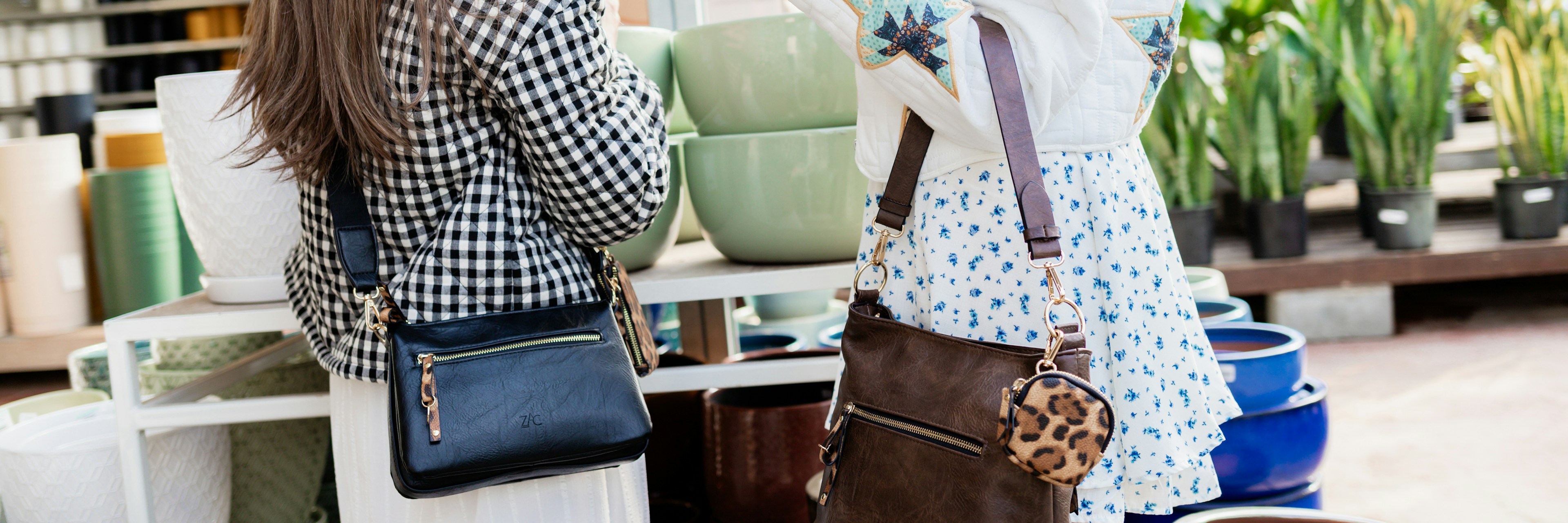 Deux femmes font leurs achats dans une jardinerie ; elles portent des tenues élégantes et des sacs à bandoulière. Elles sourient, de dos, et sont entourées de divers pots en céramique colorés et de plantes vertes.
