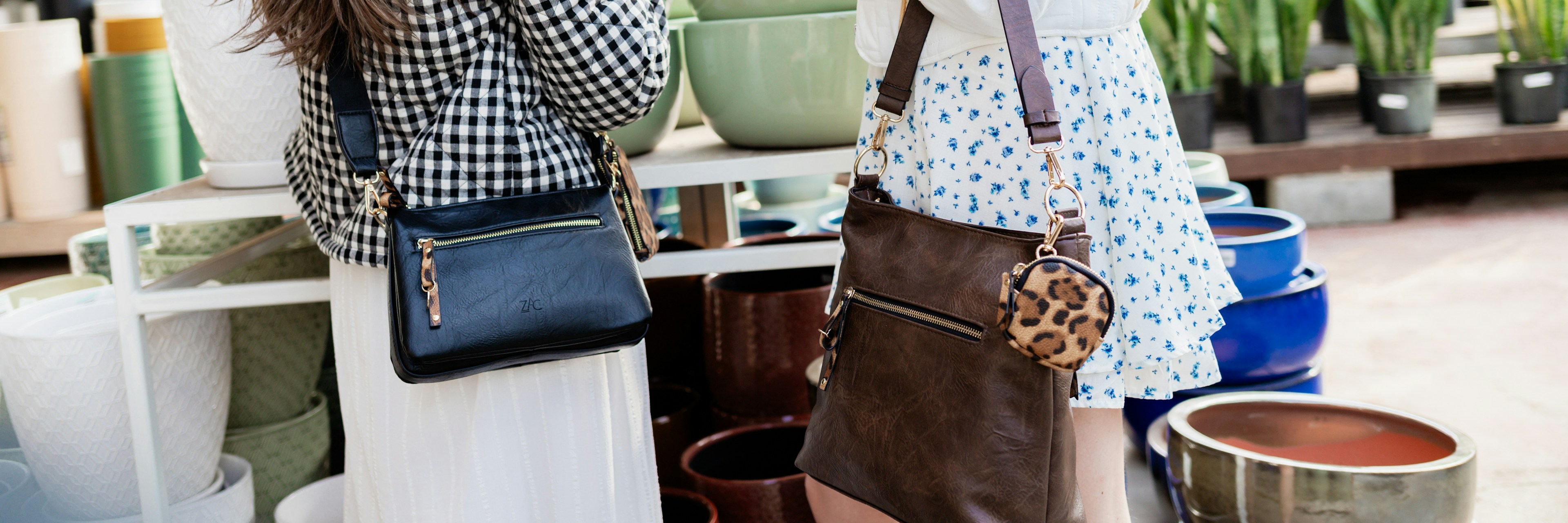 Two women stand in a plant shop, each carrying handbags. One wears a checkered jacket, the other a white jacket with star patches. Colorful pots and green plants are visible in the background.