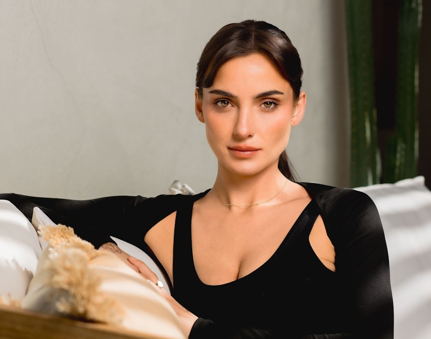black haired woman sitting on couch with arm on pillow