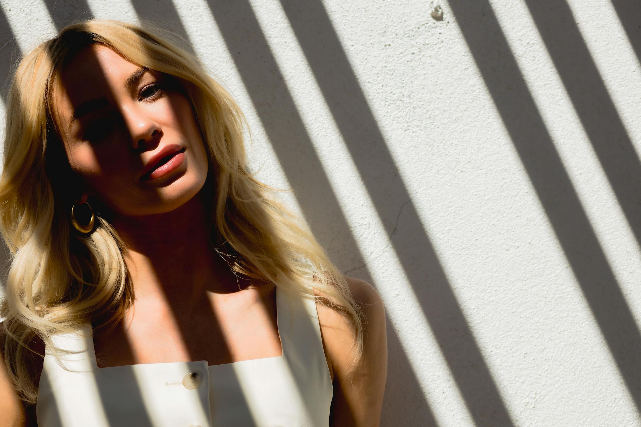 Woman posing against a wall with shadows on her
