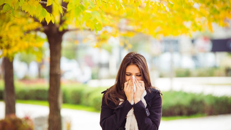 woman sneezing into tissue