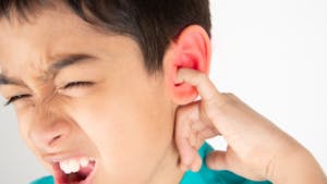 child putting his finger in his ear in pain