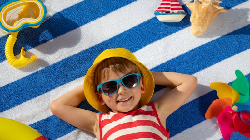 kid surrounded by beach toys