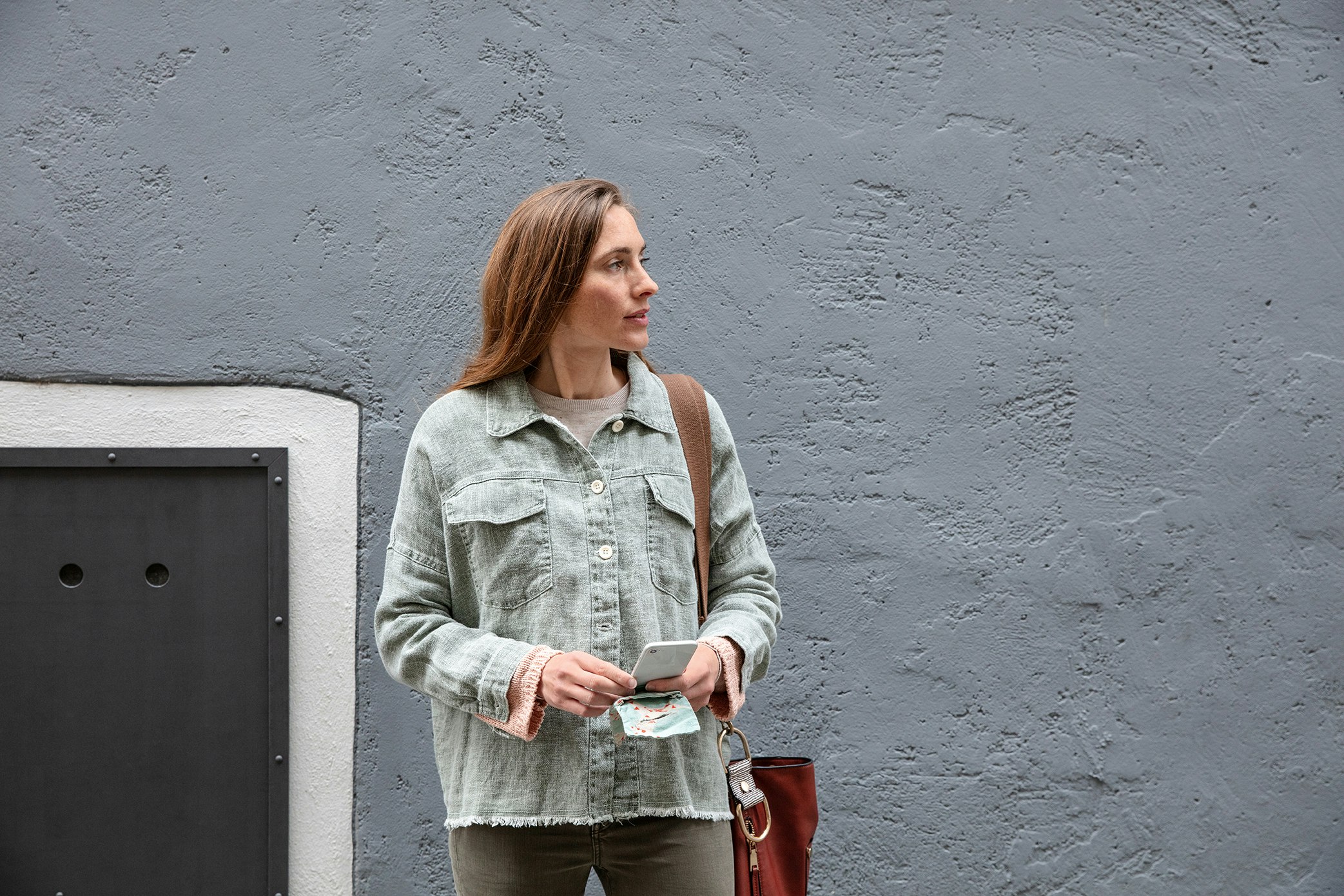 Frau steht vor Hauswand