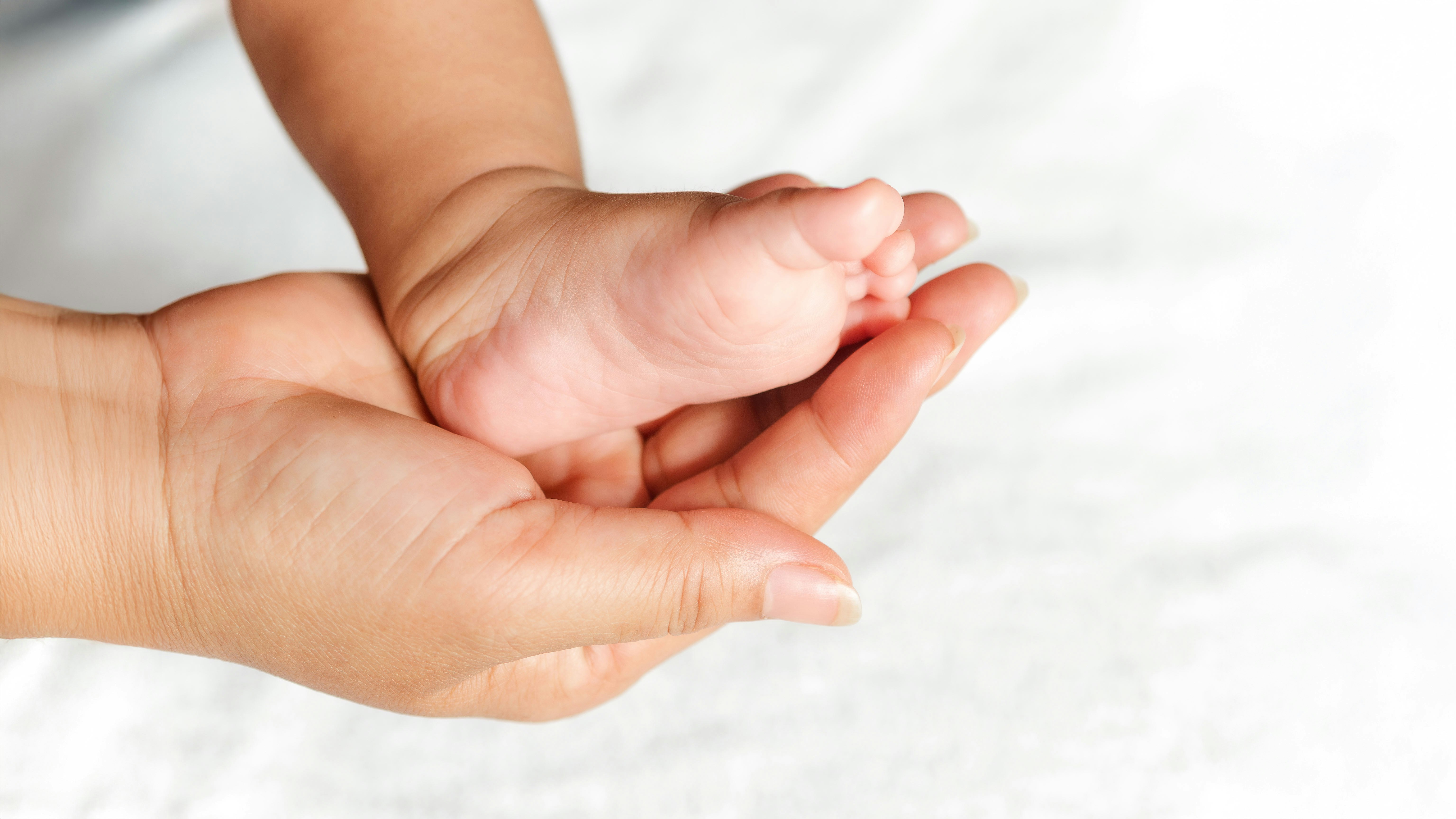 Frauenhand hält Babyfuss