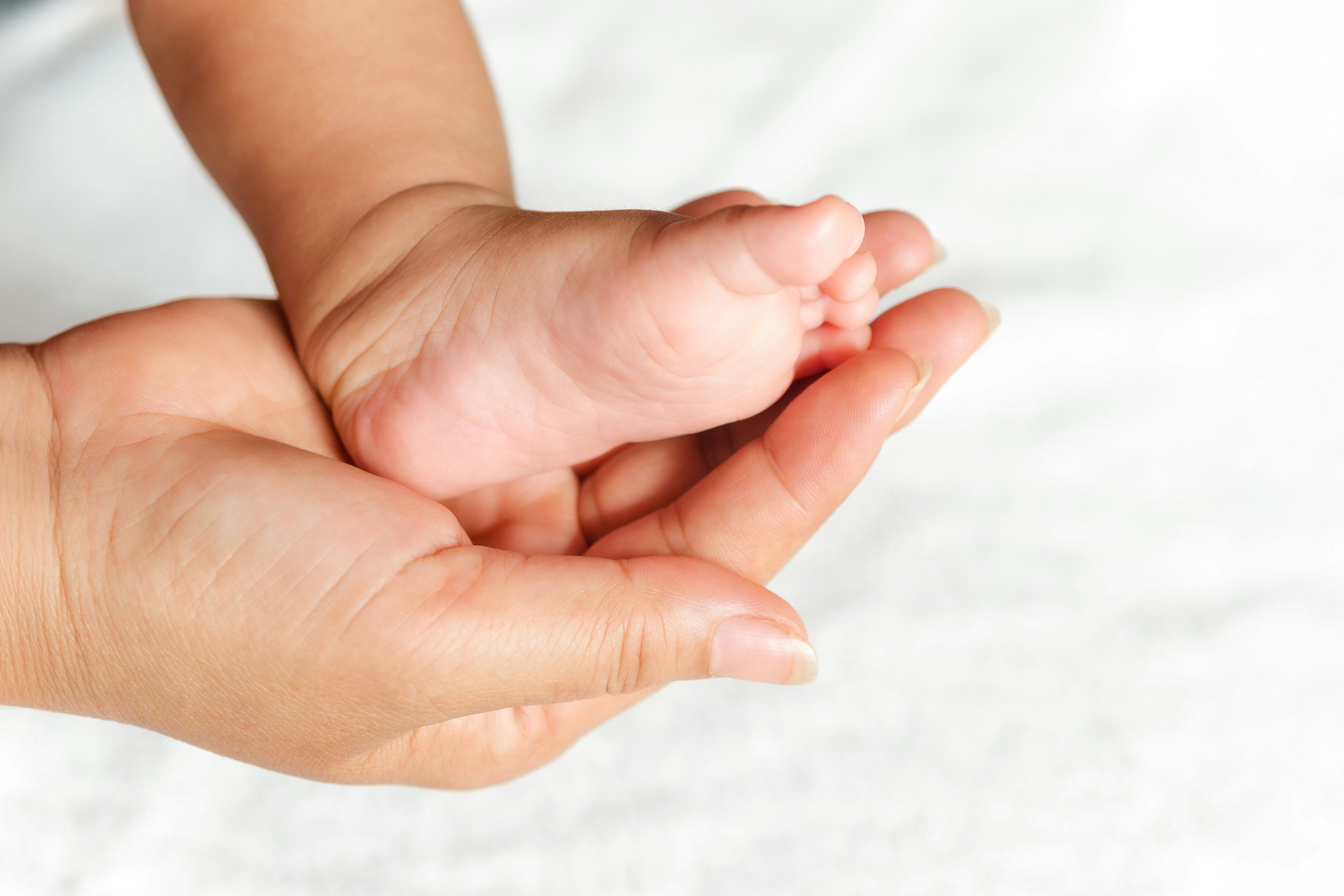 Frauenhand hält Babyfuss Frauenhand hält Babyfuss