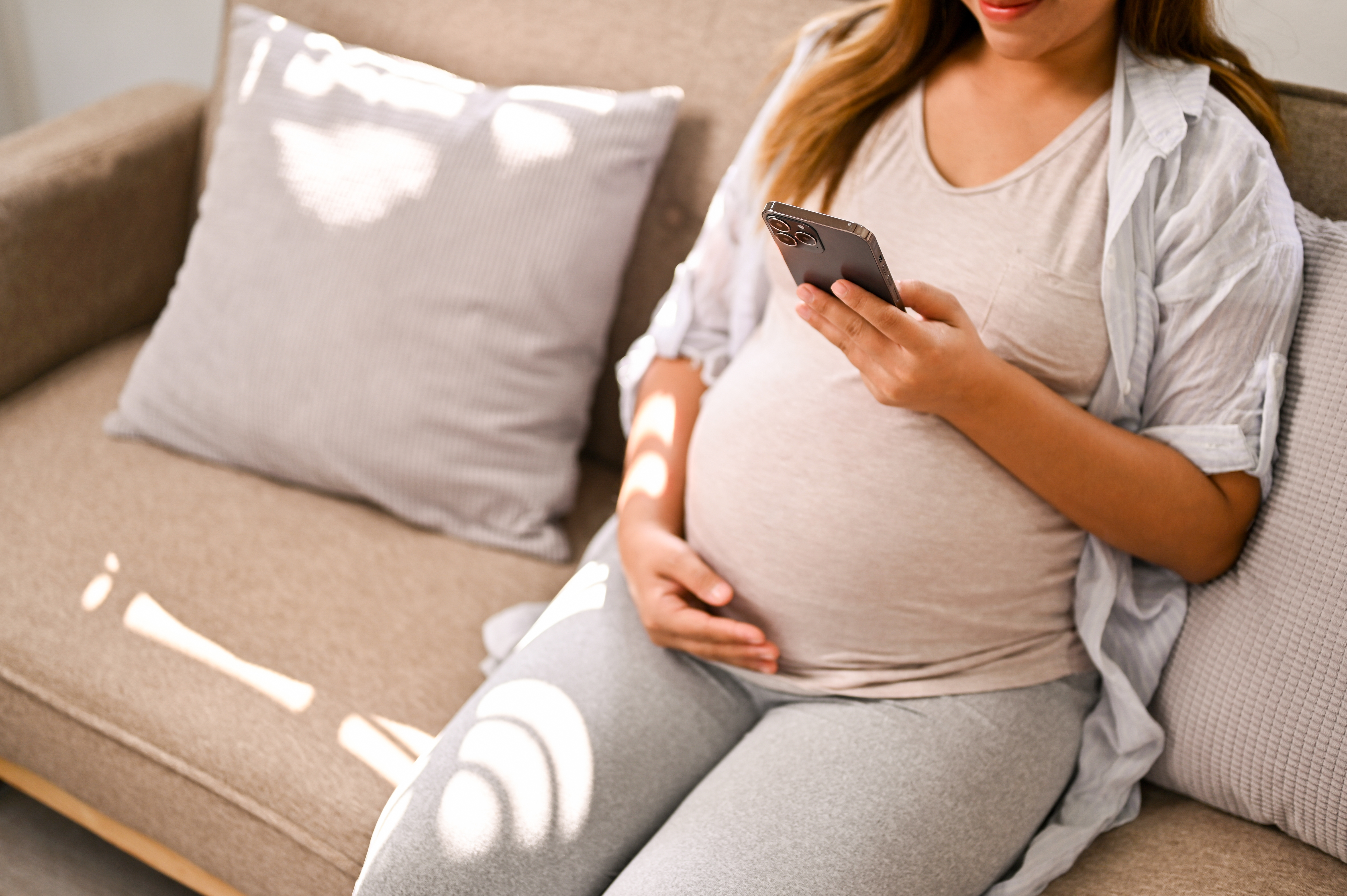 schwangere frau auf dem sofa sitzend, am handy schwangere frau auf dem sofa sitzend, am handy