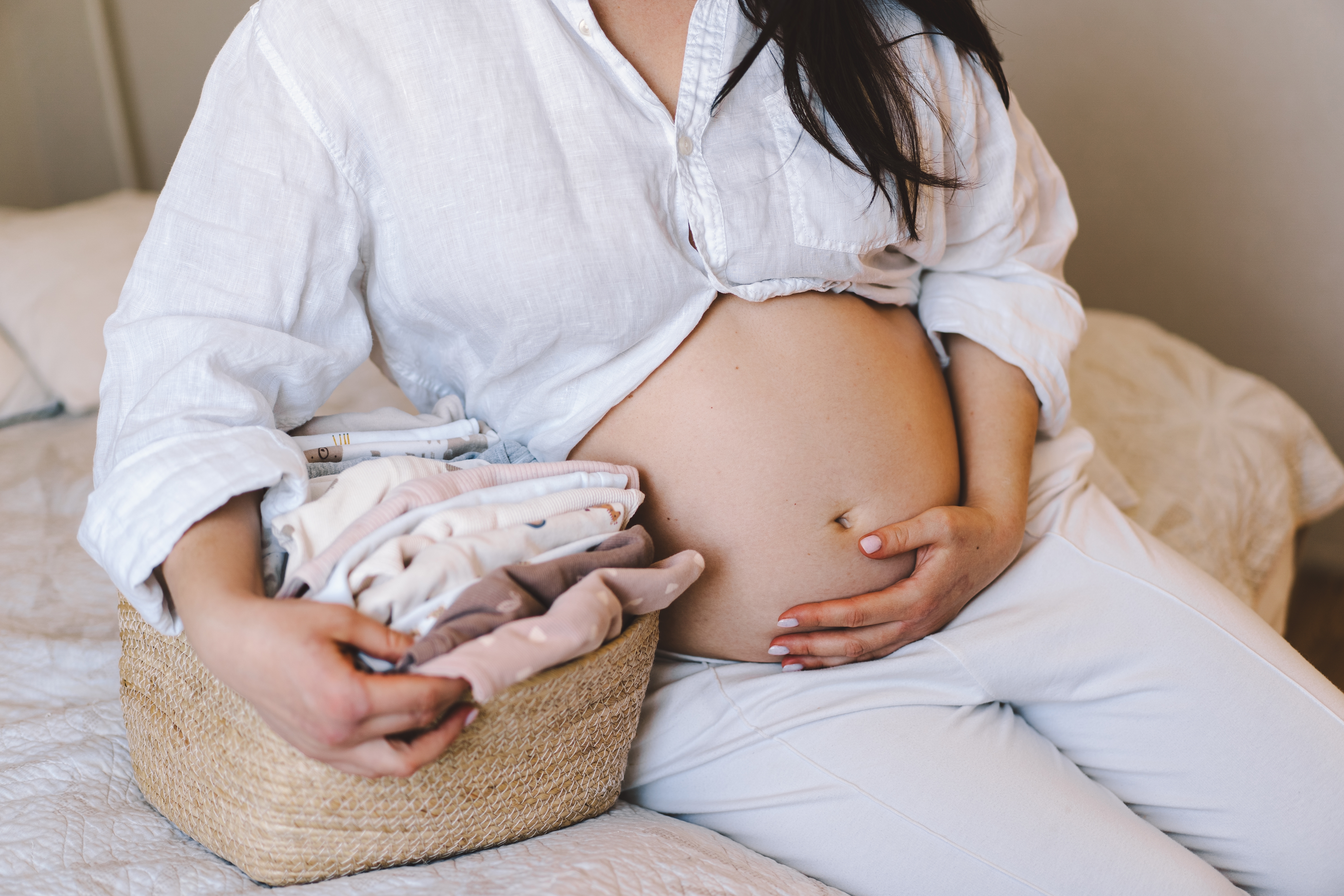 schwangere_frau_mit_babykleidung schwangere_frau_mit_babykleidung